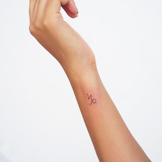 A small wrist Capricorn symbol tattoo